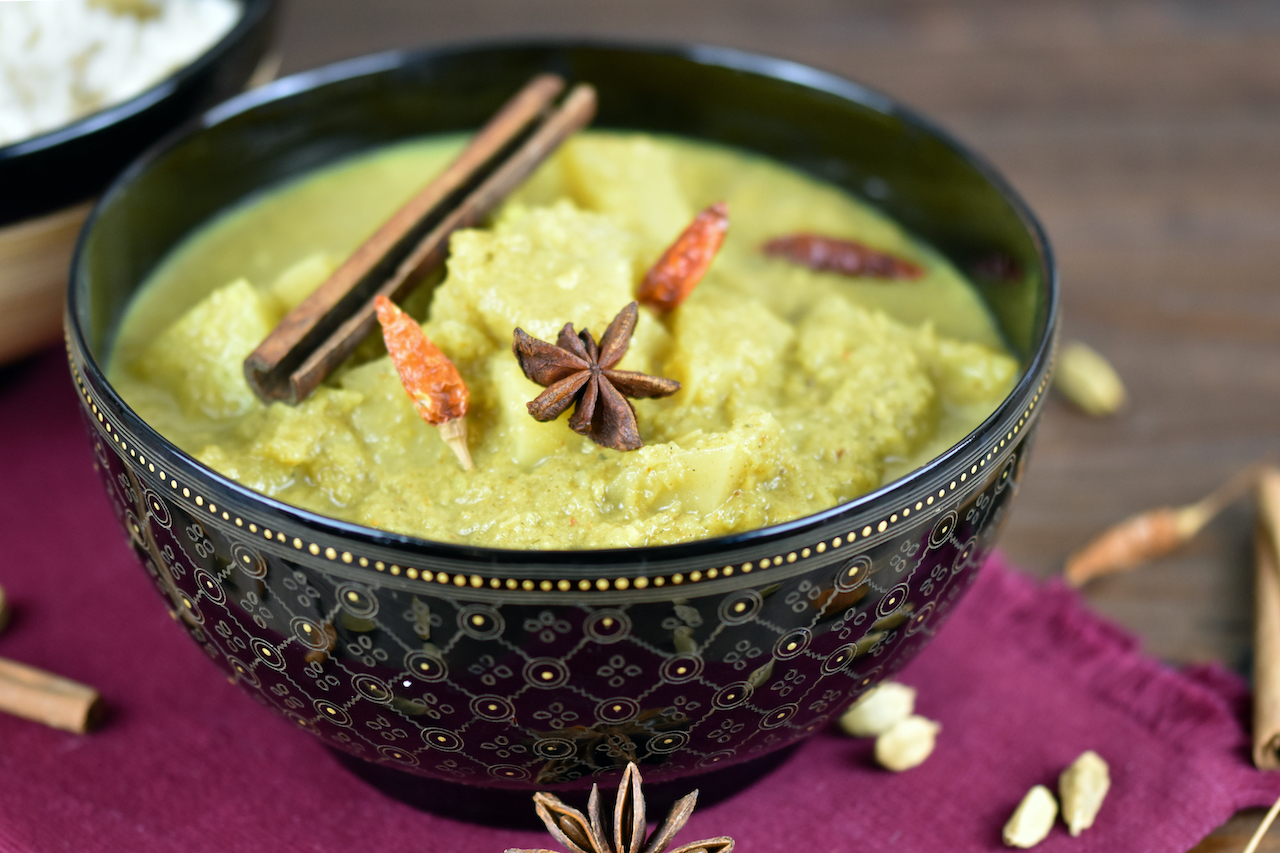 Veganes Kartoffelcurry in einer schwarzen Schale.