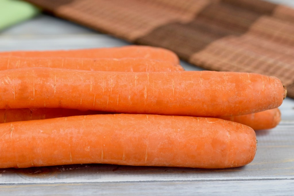 Karotteln auf hellen Holzlamellen.