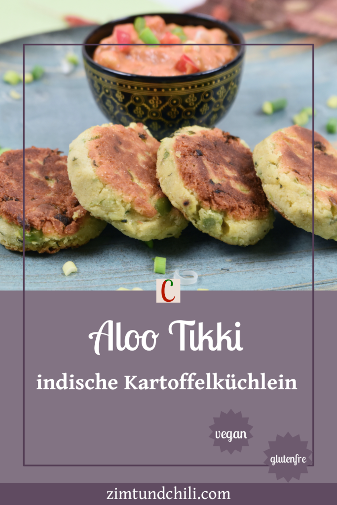 Indische Kartoffelküchlein auf blauem Teller. Dahinter steht eine Schale mit Kichererbsen-Curry. Beschrifteter Pin.