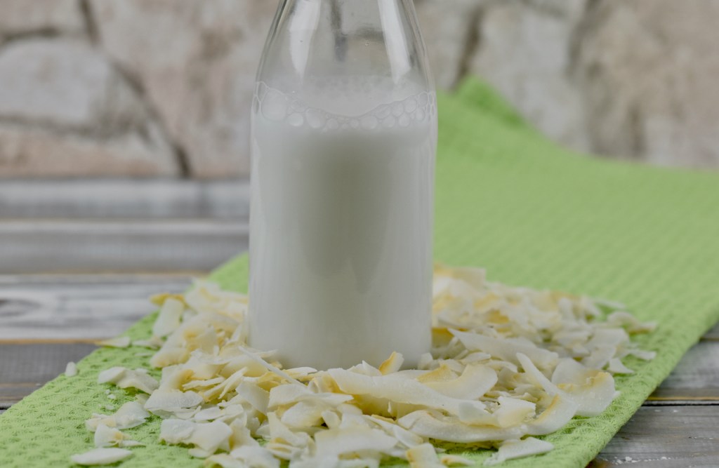 Kokosmilch in Glasflasche. Hintergrund hell.