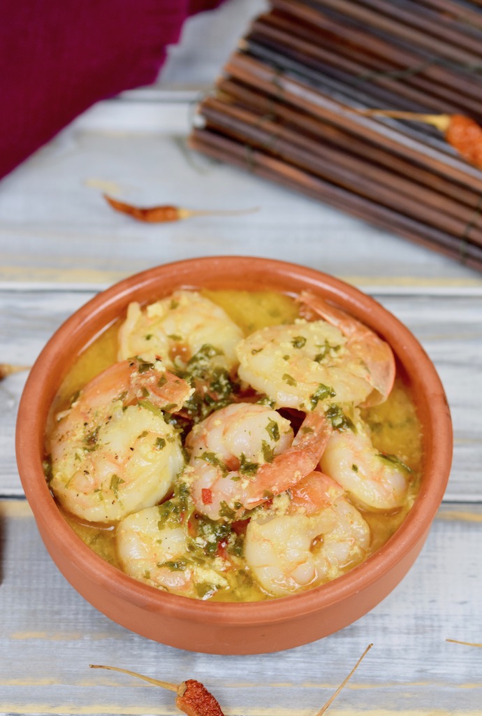 Gambas al Pil Pil in einer Knoblauch-Weißwein-Sauce in einer Tonschale. Hintergrund hell.