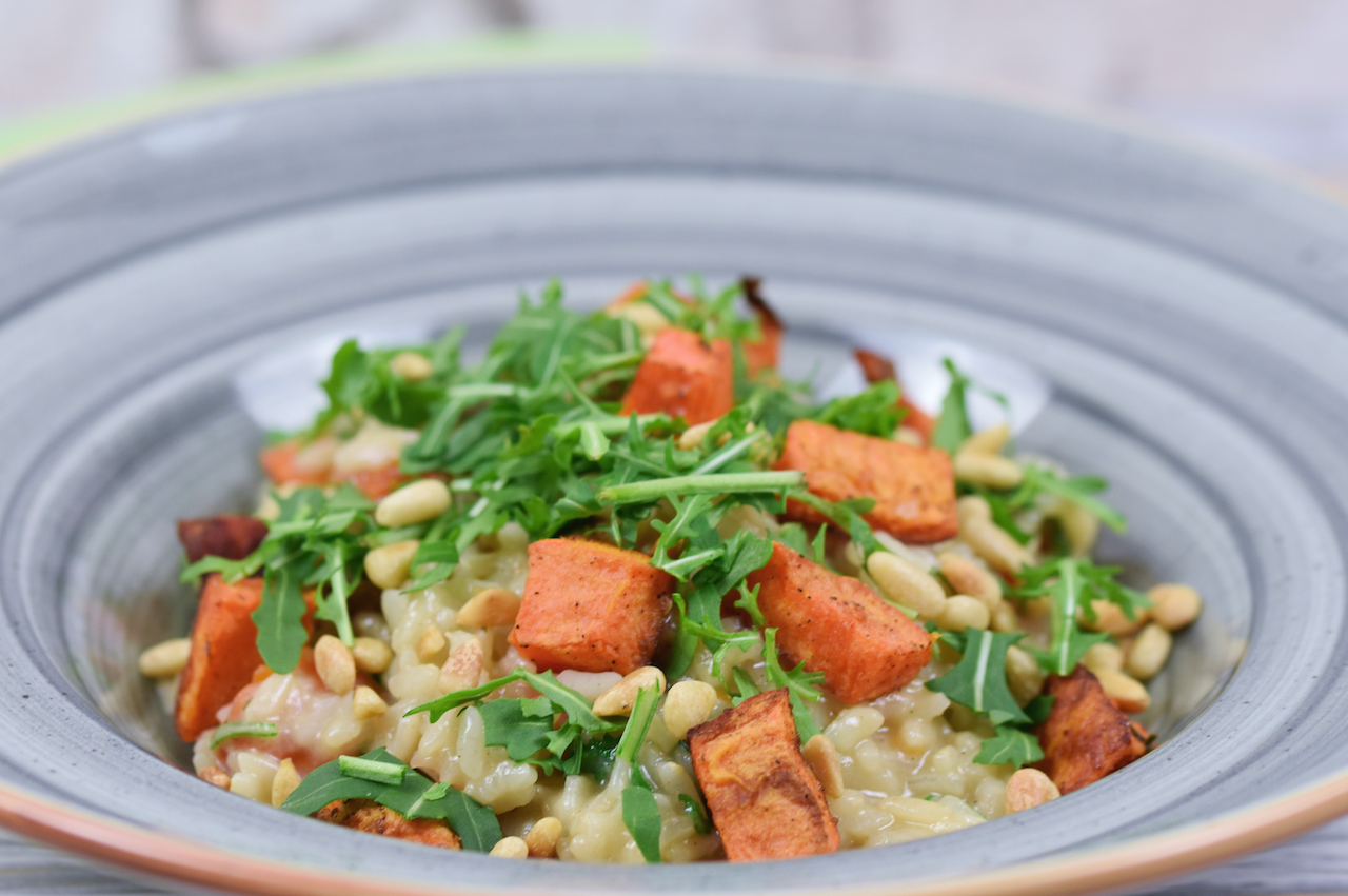Risotto mit Süßkartoffeln und Rucola auf grauem Teller.