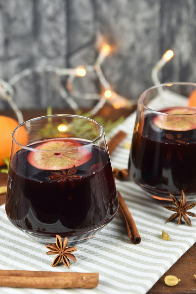Klassischer Glühwein in 2 Gläsern auf hellem Tuch. Hintergrund dunkel.