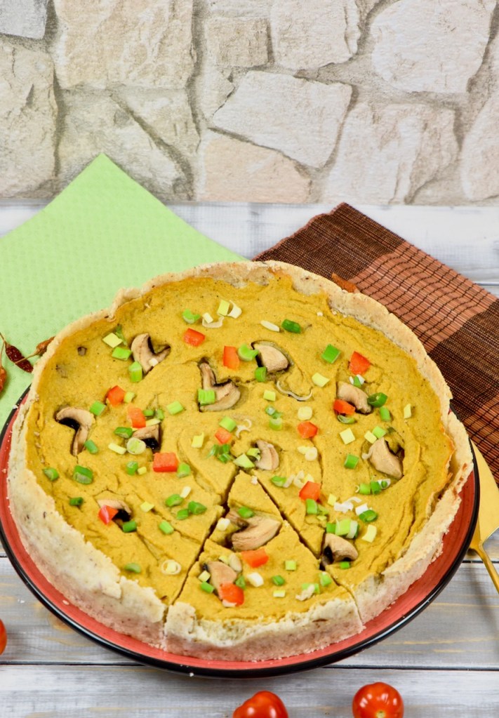 Glutenfreie Quiche mit Pilzen garniert mit Champignons, Paprika und Frühlingszwiebeln. Hintergrund hell. Hochkant