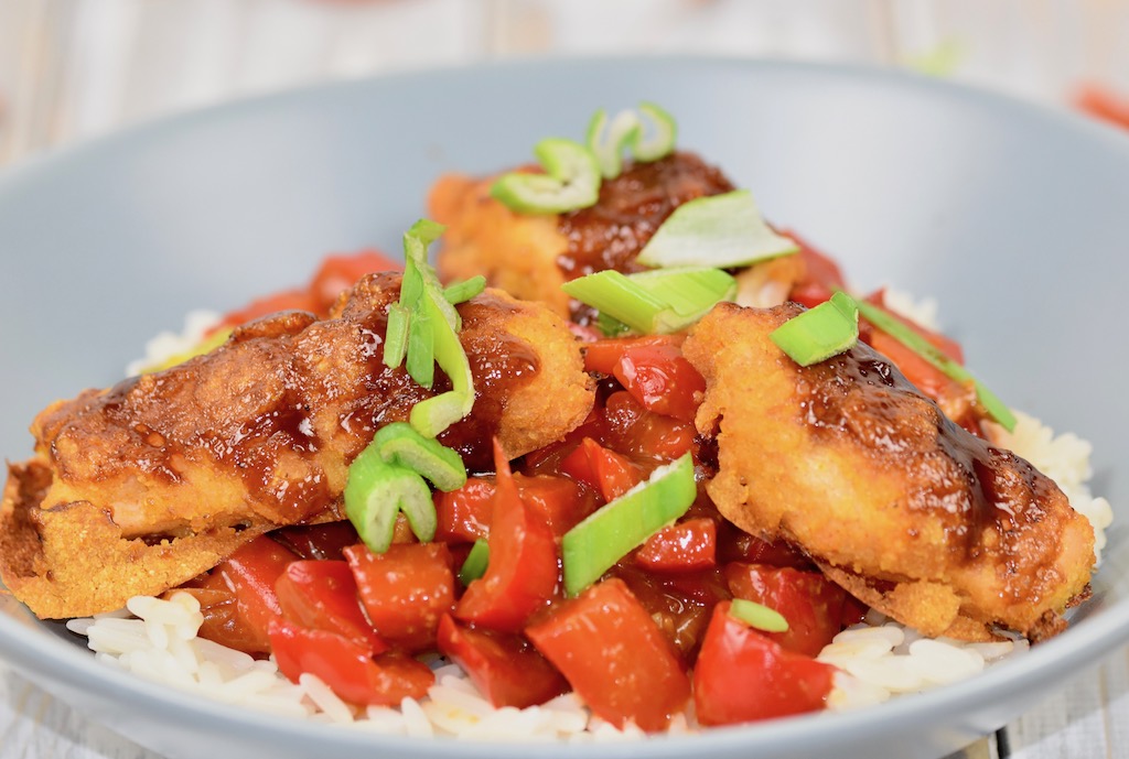 Gebackenes Hoisin-Hähnchen auf Paprikagemüse mit Reis in hellgrauem Teller. Nahaufnahme.