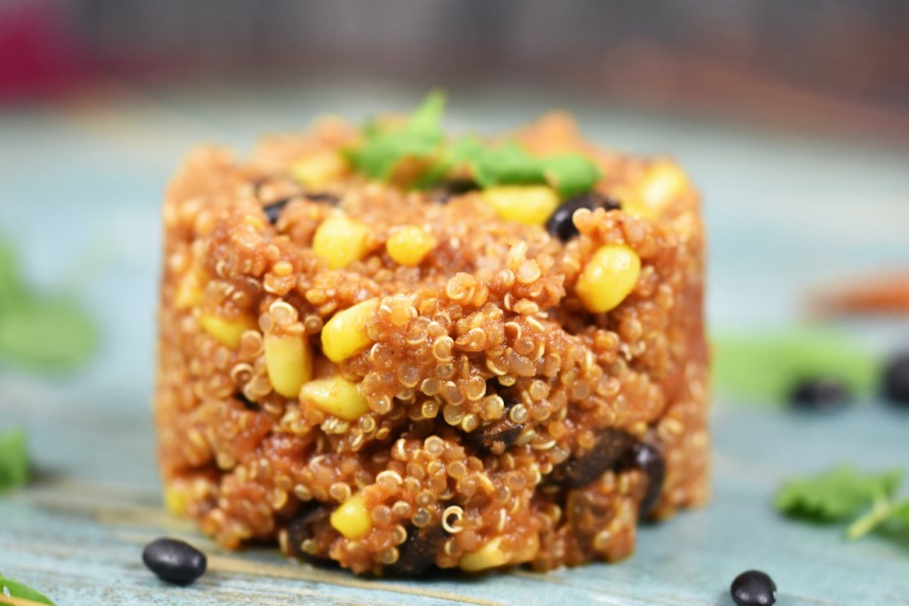 Quinoa-Pfanne auf mexikanische Art auf blauem Teller.