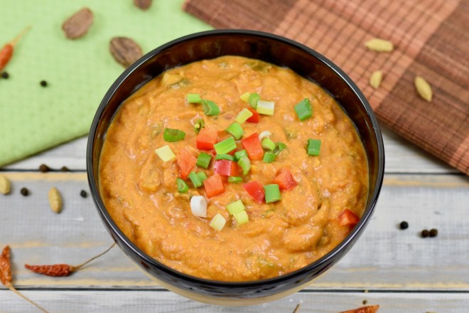 Chickpea Tikka Masala in asiatischer Bowl garniert mit Frühlingszwiebeln und roter Paprika. Hintergrund hell.