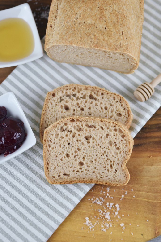 Glutenfreies Sandwichbrot teilweise angeschnitten auf Walnussbrett.