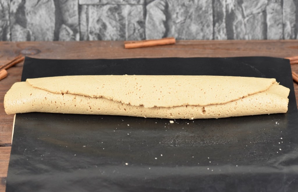 aufgerollter Teig (Teigrolle) auf dunklem Hintergund