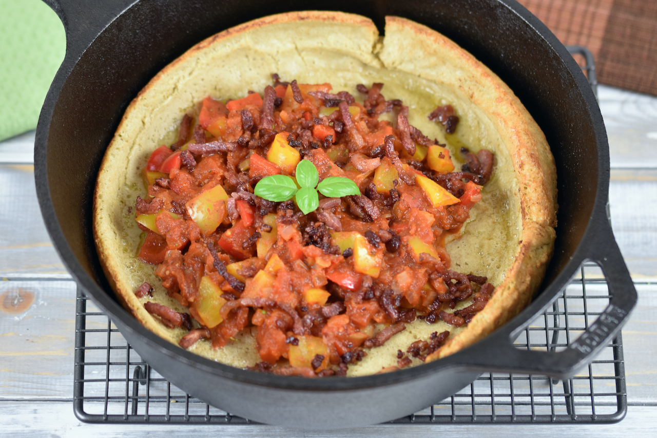 Herzhaftes Dutch Baby mit Paprikagemüse in einem schwarzen gusseisernen Topf.