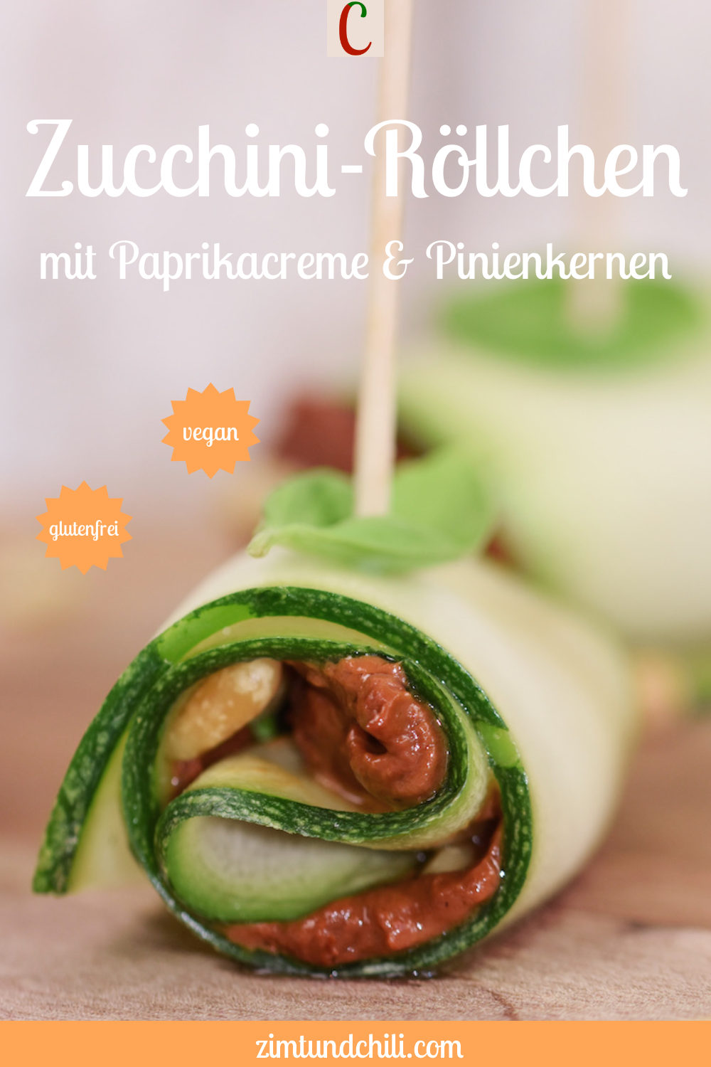 Zucchini-Röllchen mit Paprikacreme und Pinienkernen gefüllt auf Holzbrett. Beschrifteter Pin.