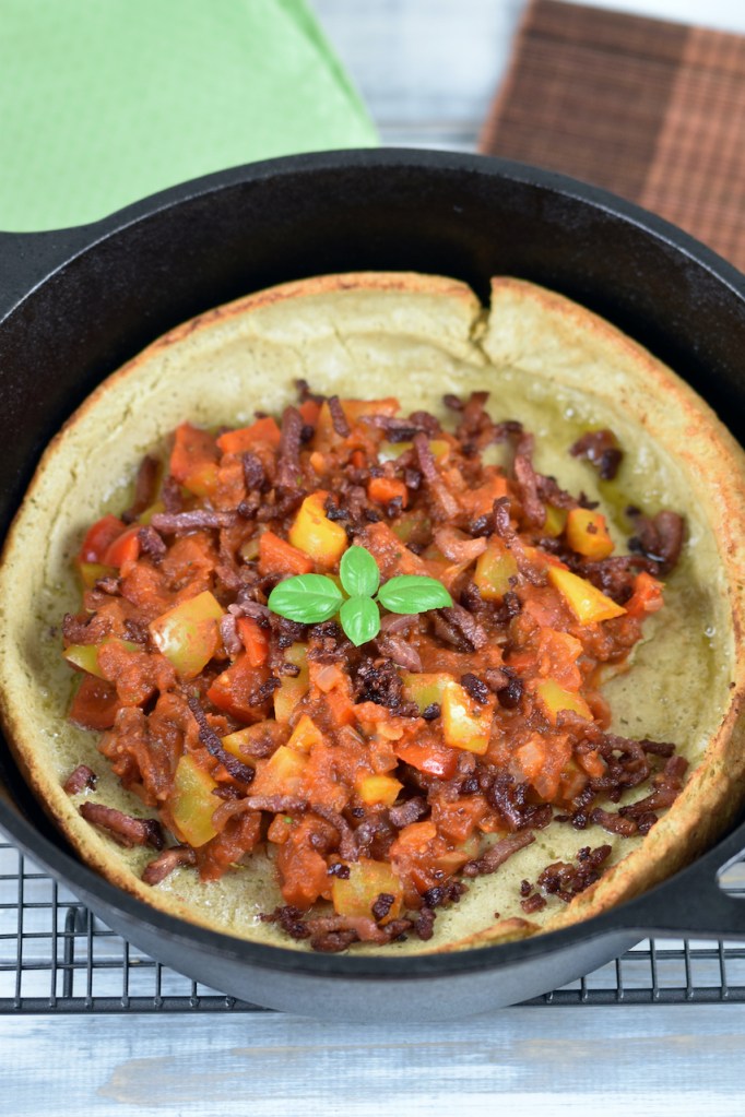 Herzhaftes Dutch Baby mit Paprikagemüse in einem schwarzen gusseisernen Topf.