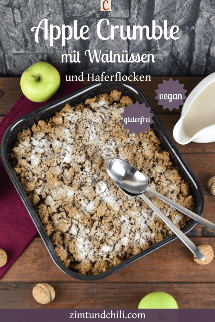Apple Crumble mit Walnüssen und Haferflocken in einer Auflaufform. Hintergrund dunkel. Beschrifteter Pin.