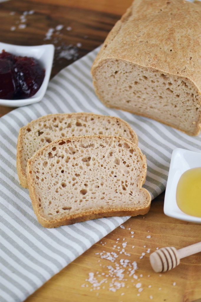 Glutenfreies Sandwichbrot teilweise angeschnitten auf Walnussbrett.