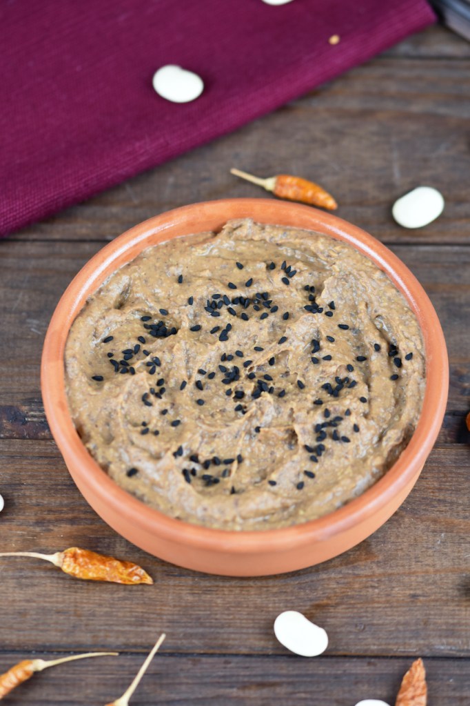 Rauchige schwarze Bohnencreme in einer Tonschale. Hintergrund dunkel.