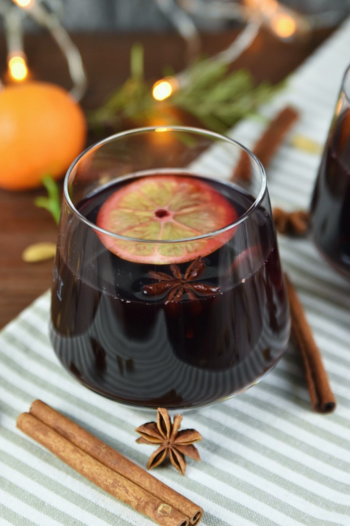 Klassischer Glühwein in einem Glas auf hellem Tuch. Hintergrund dunkel.