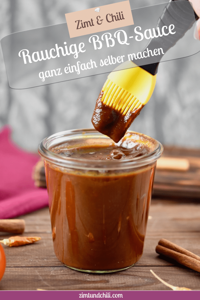 Rauchige BBQ-Sauce in einem Glas. Ein Pinsel mit gelben Silikonborsten wird in die Sauce getunkt. Hintergrund dunkel. Pin beschriftet.