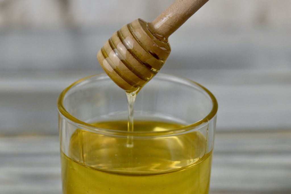 Honig in einem Glas mit Honiglöffel aus Holz.