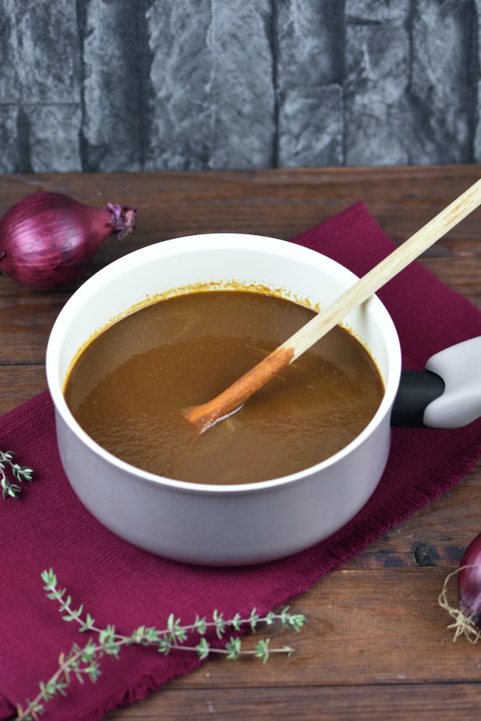 Würzige vegane Bratensauce in einem kleinen Topf. Hintergrund dunkel.