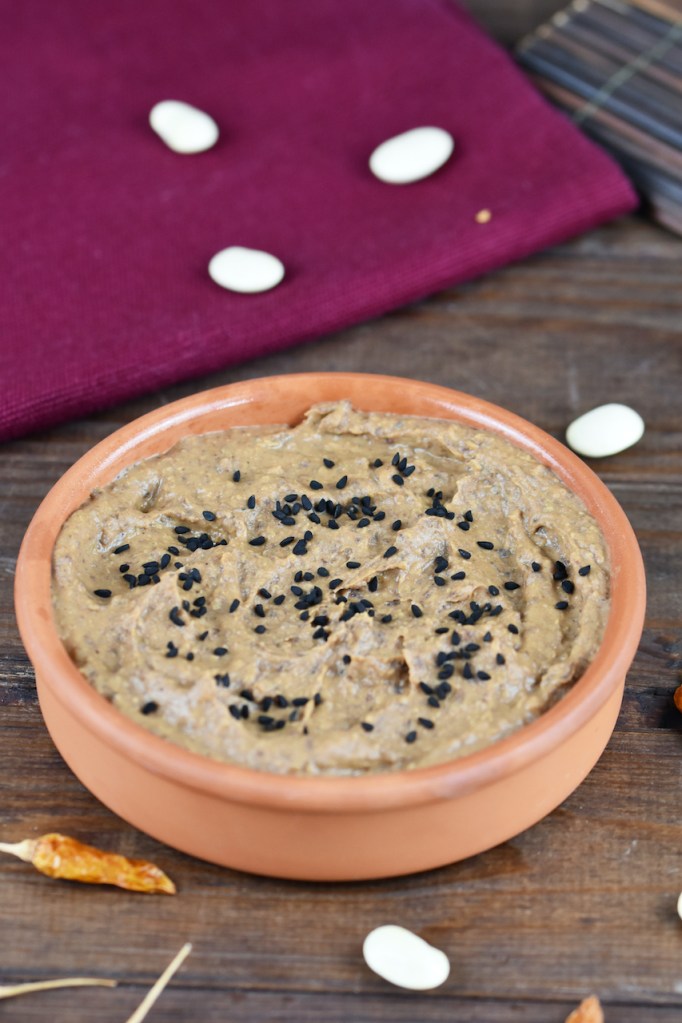 Rauchige schwarze Bohnencreme in einer Tonschale. Hintergrund dunkel.