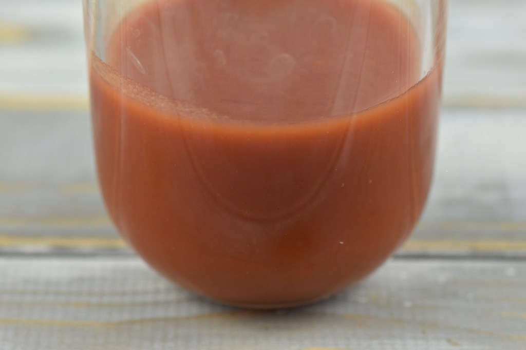 passierte Tomaten in Glasflasche. Hintergrund hell.