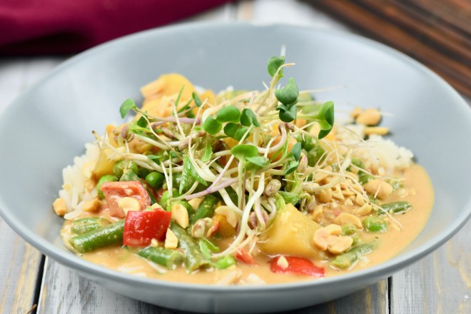 Rotes Thai-Curry mit Kokosmilch in einem grauen, tiefen Teller.