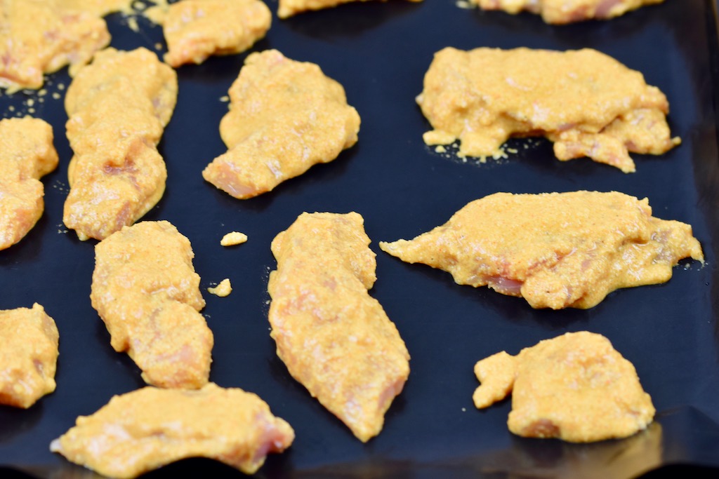 Hähnchennuggets im Teigmantel auf einem Backblech.