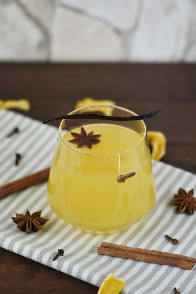 Weißer Glühwein mit Vanille und Orange in einem Glas ohne Stiel.