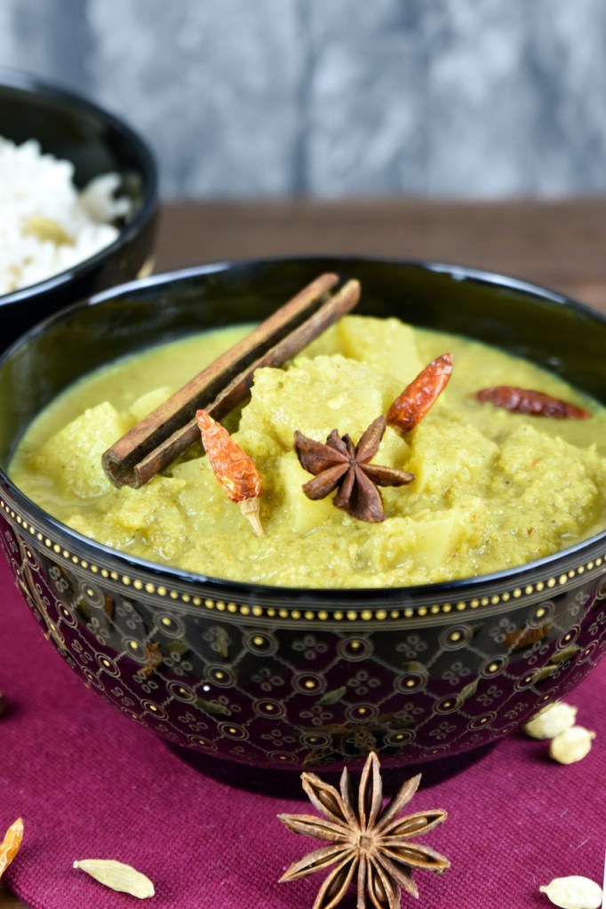 Veganes Kartoffelcurry in einer schwarzen Schale.