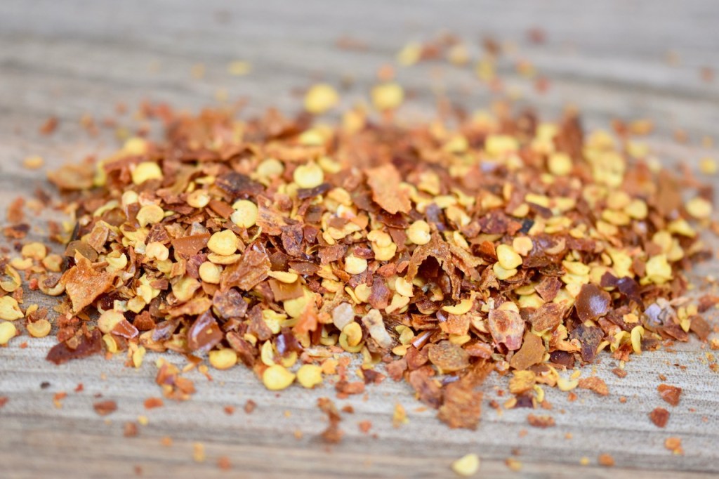 rote Chiliflocken lose, Hintergrund Holz