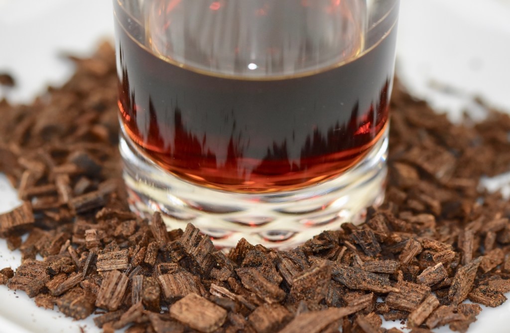 Vanillearoma in kleinem Glas. Das Glas steht zwischen zerkleinerten Vanilleschoten.