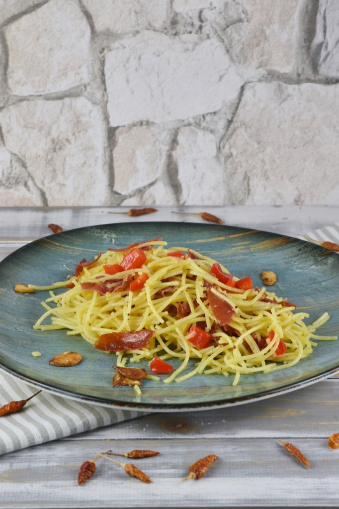 Spaghetti aglio e olio e peperoncino auf einem türkisen Teller.