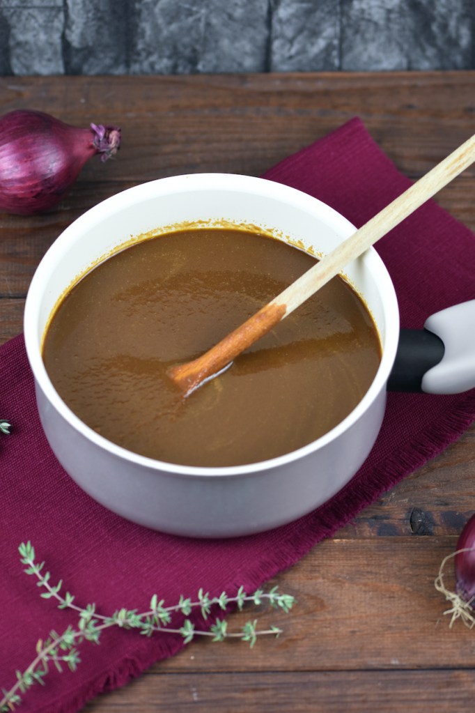 Würzige vegane Bratensauce in einem kleinen Topf. Hintergrund dunkel.