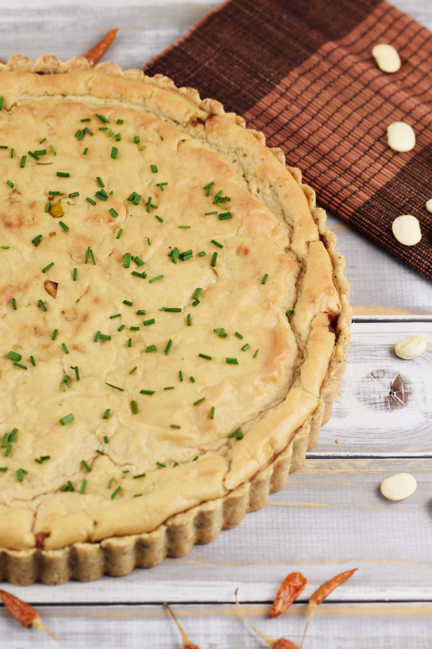 Runde Quiche Lorraine mit Lauch, halb zu sehen. Hintergrund hell.