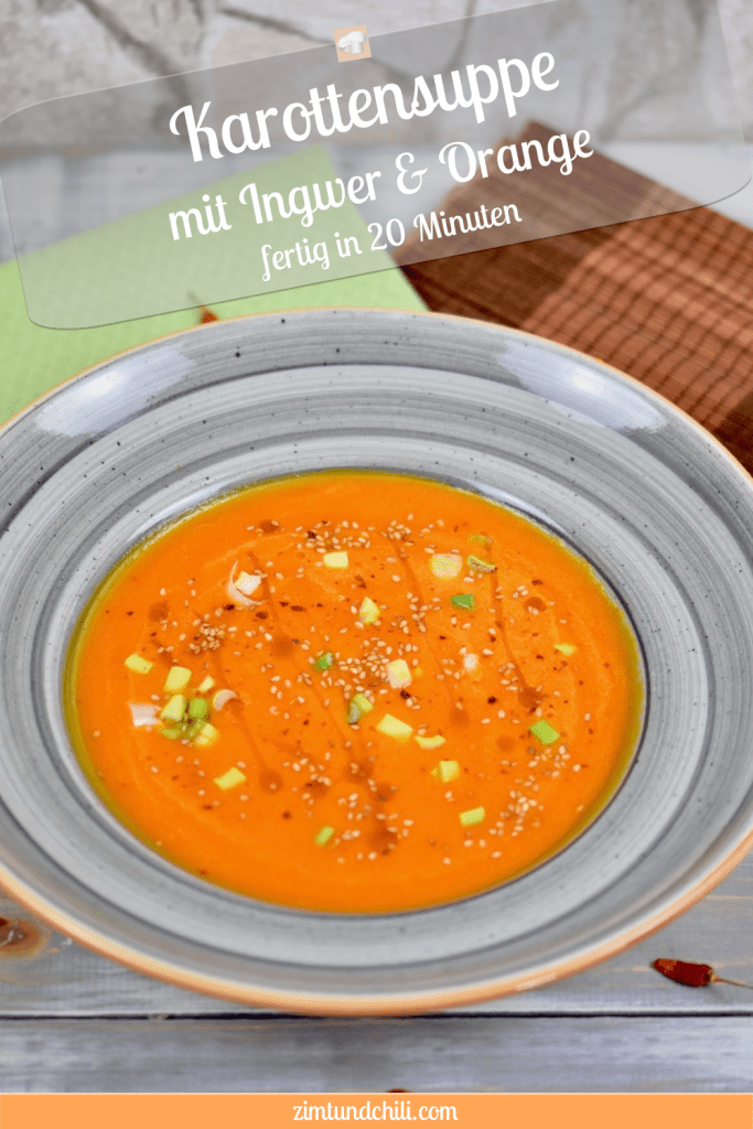 Karottensuppe mit Ingwer und Orange in grauem Teller. Garniert mit Sesamsamen, Sesamöl und Frühlingszwiebeln. Hintergrund hell. Pin beschriftet
