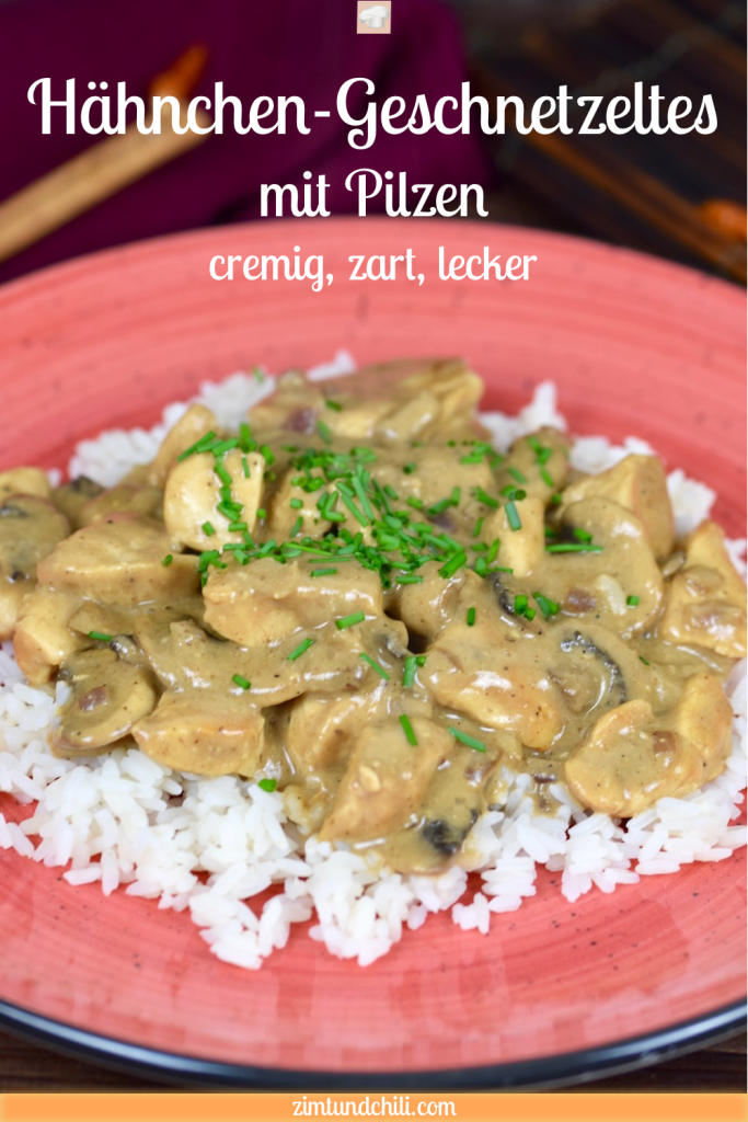 Hähnchen-Geschnetzeltes mit Pilzen auf Reis auf einem roten Teller, dekoriert mit Schnittlauchröllchen. Hintergrund dunkel. Bild beschriftet