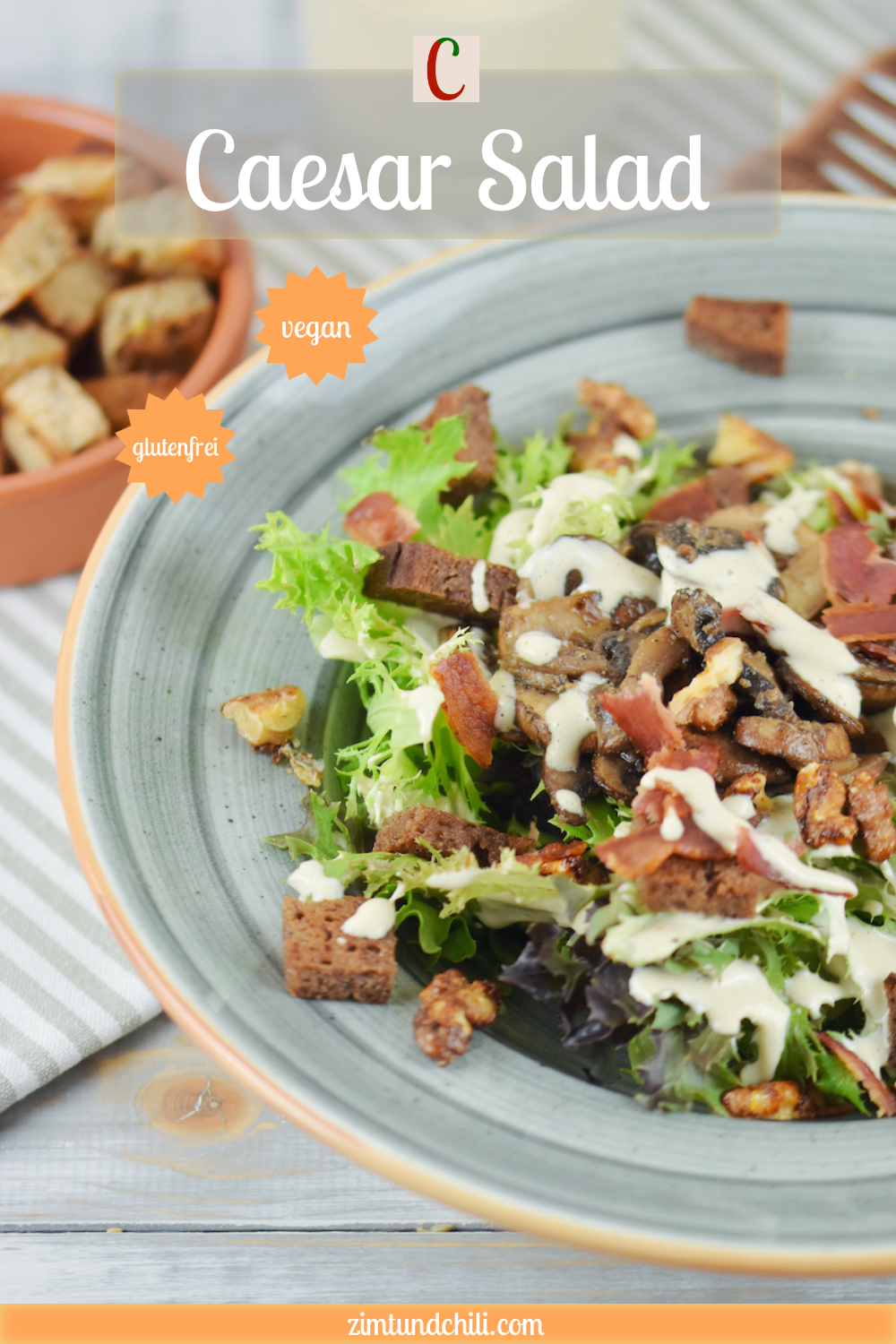 Veganer Caesar Salad mit Pilzen und Walnüssen auf grauem Teller. Hintergrund hell. Beschrifteter Pin.