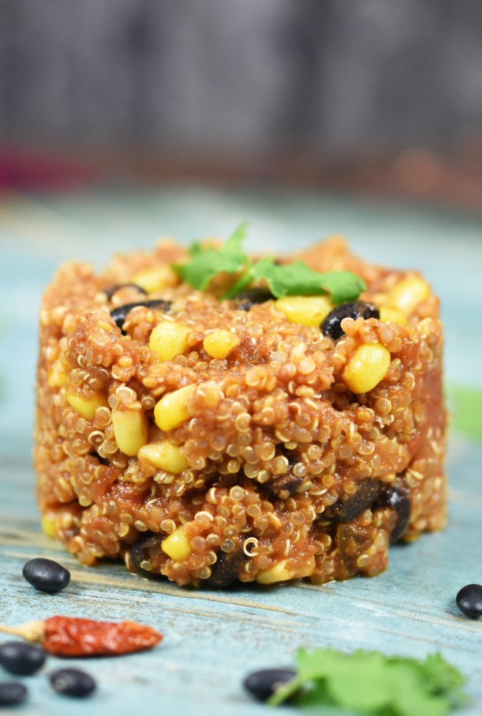 Quinoa-Pfanne auf mexikanische Art auf blauem Teller. Hintergrund dunkel.