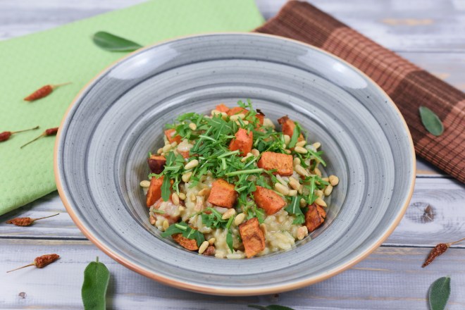 Risotto mit Süßkartoffeln und Rucola auf grauem Teller.