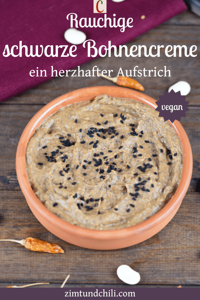 Rauchige schwarze Bohnencreme in einer Tonschale. Hintergrund dunkel. Beschrifteter Pin.