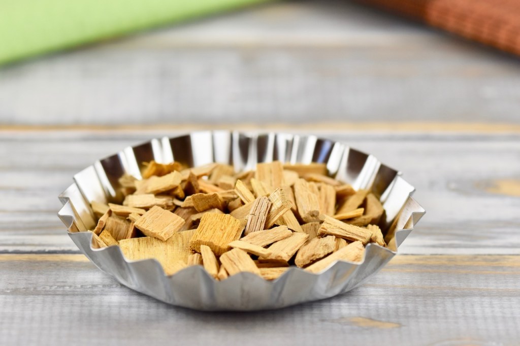 Muffinform aus Metall mit Räucher-Chips gefüllt. Hintergrund hell.