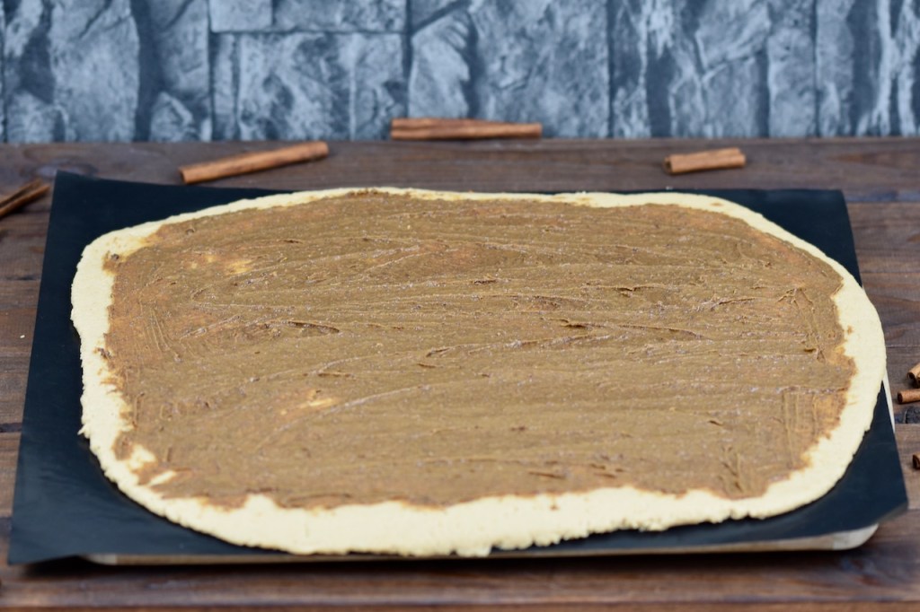 Teig bestrichen mit Zimtcreme, Hintergrund dunkel