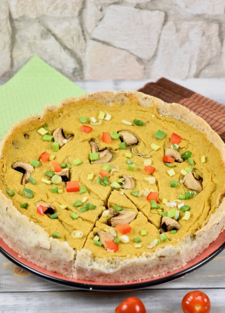 Glutenfreie Quiche mit Pilzen garniert mit Champignons, Paprika und Frühlingszwiebeln. Hintergrund hell. Hochkant