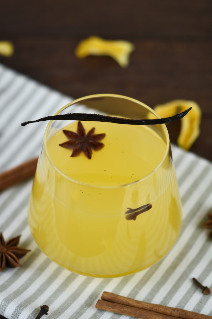 Weißer Glühwein mit Vanille und Orange in einem Glas ohne Stiel.