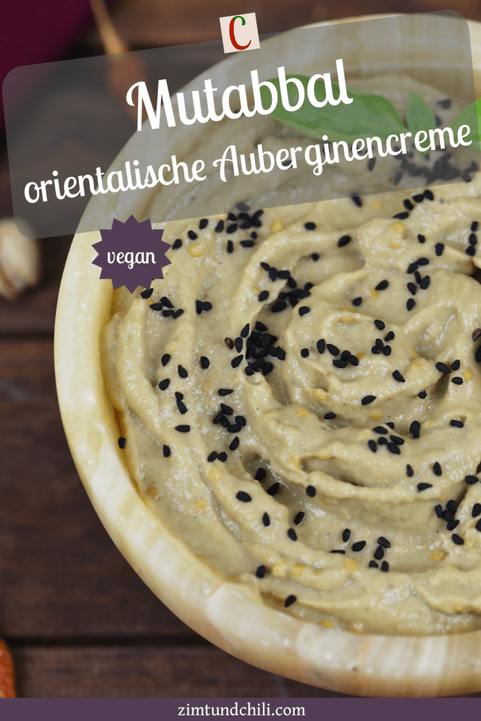 Orientalisches Mutabbal in einer Schale garniert mit Schwarzkümmelsamen und Basilikum. Hintergrund dunkel.