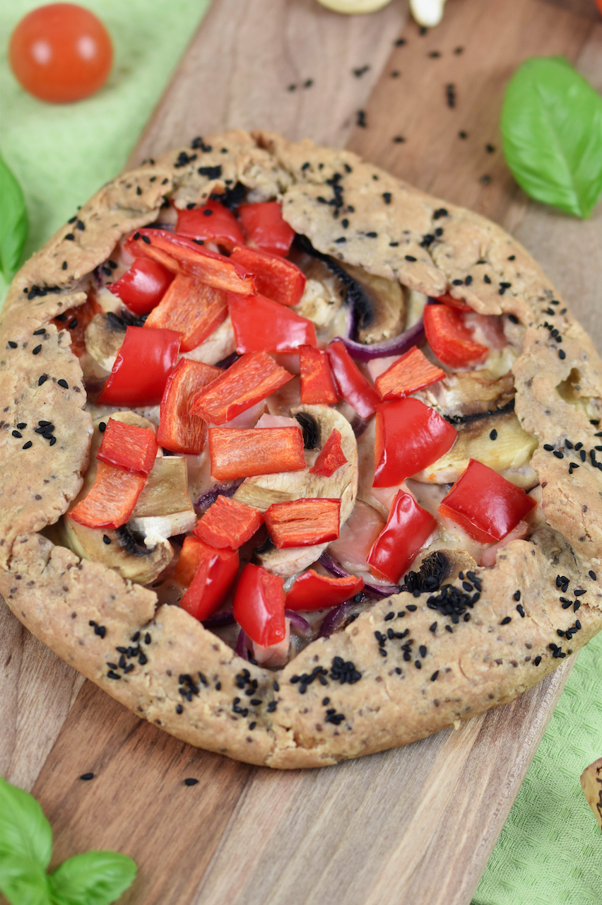 Knusprige Galette mit Paprika und Pilzen auf Holzbrett.