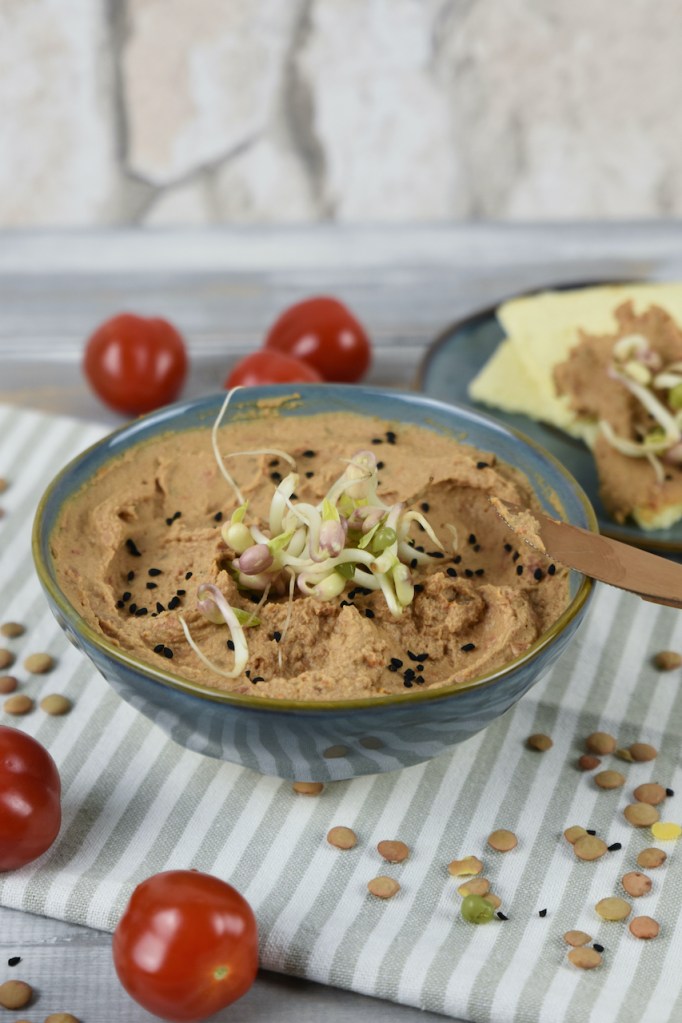 Linsen-Tomaten-Aufstrich mit Tahini in einer grauen Schale. Hintergrund hell.