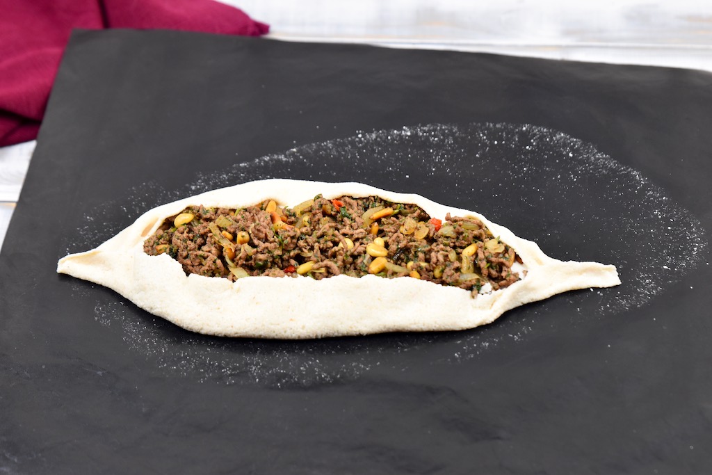 Pizzateig gefüllt mit Hack und zu einem Schiffchen geformt.