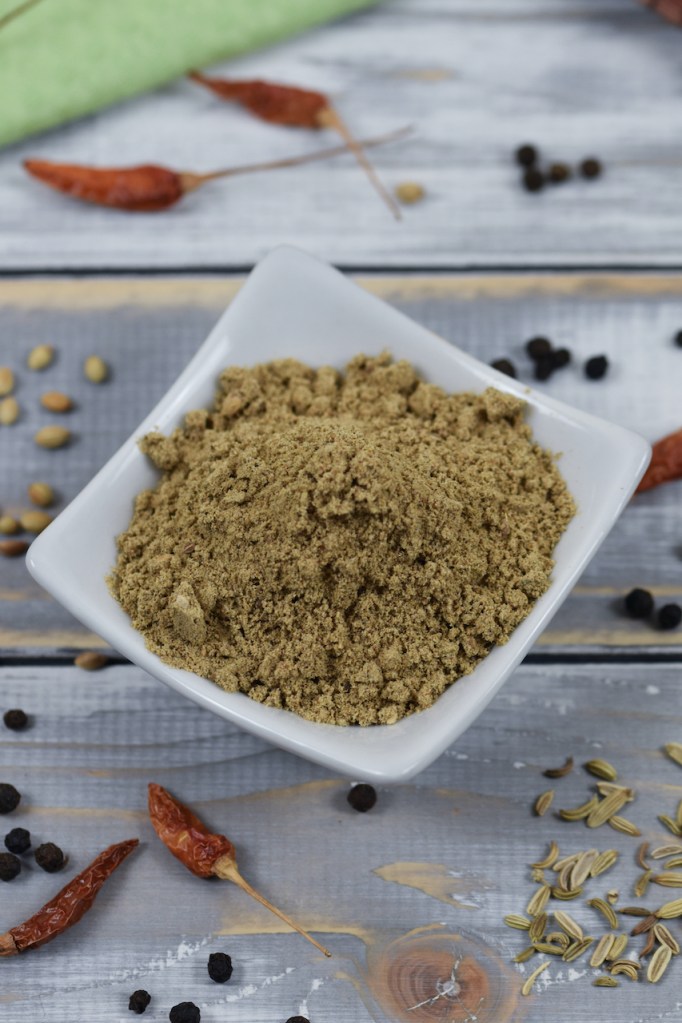 Chat Masala in weißer Schale. Heller Hintergrund, dekoriert mit Gewürzen.