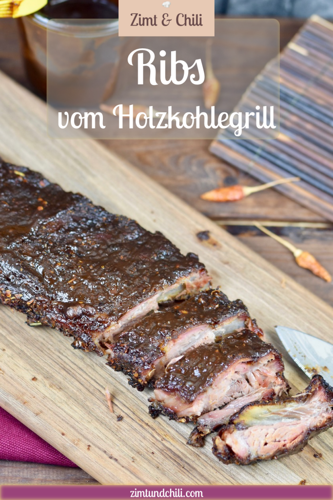 Ribs vom Holzkohlegrill auf Holzbrett. Ein Teil ist angeschnitten. Hintergrund dunkel. Pin beschriftet.